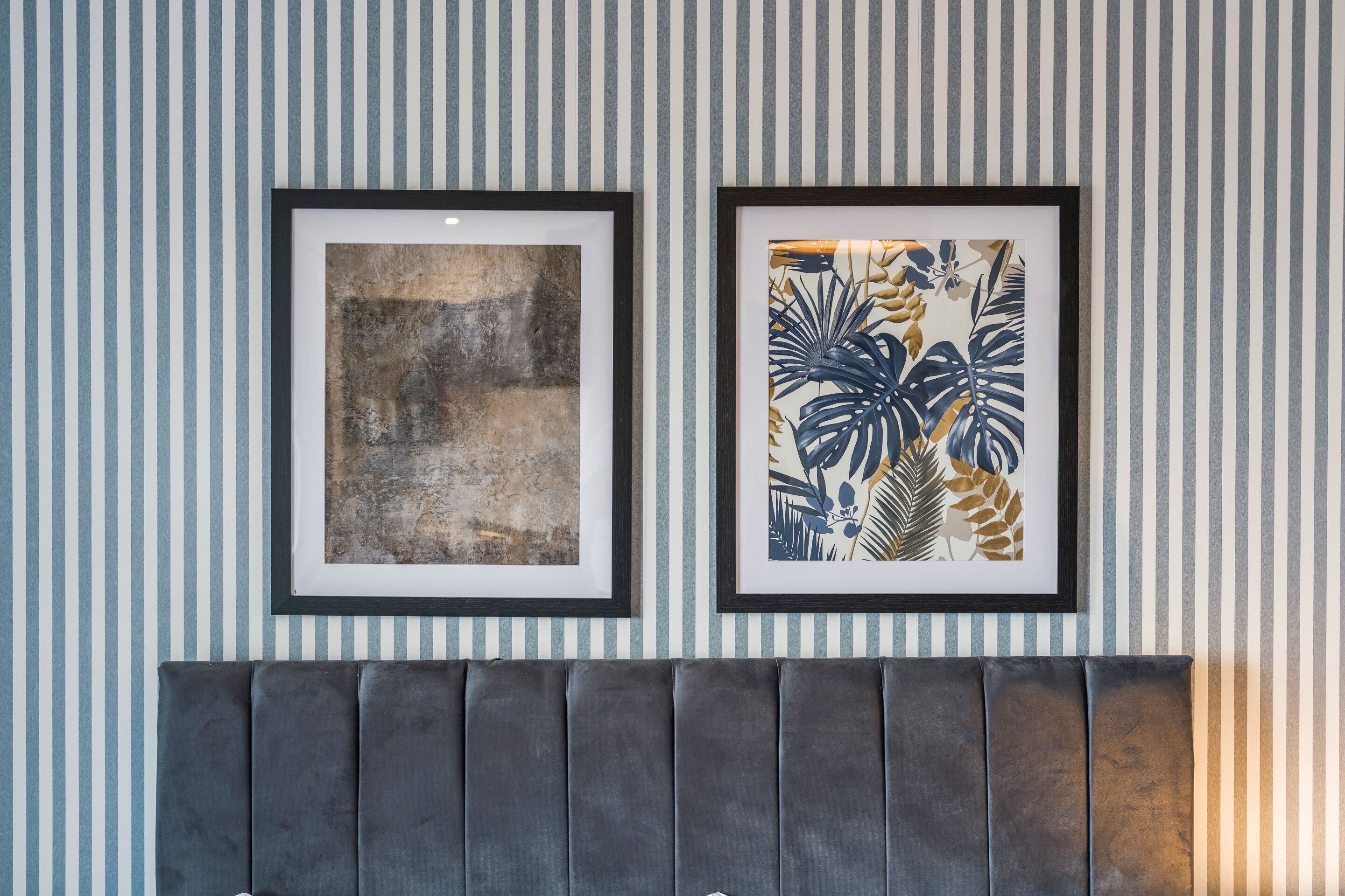Two framed artworks on a wall with a striped pattern.
