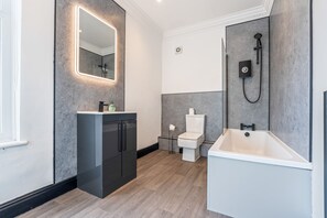 Un baño moderno con un espejo grande, un inodoro, una bañera y una cabina de ducha.