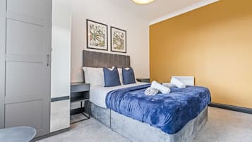 Une chambre à coucher comprenant un lit, des tables de chevet, une armoire et deux tableaux encadrés accrochés au mur.