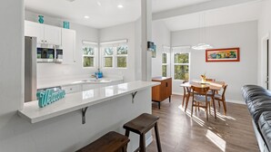 A modern kitchen with white cabinetry, a large island, and a dining area with wooden furniture. - Mountain, Canyon & Golf Course Views from all Windows in this corner 3 bedrm (Tucson)