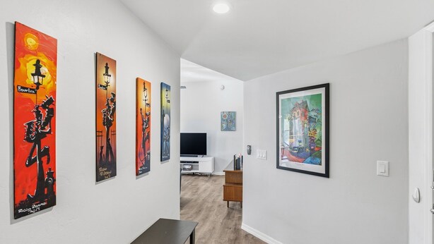A hallway with artwork on the walls, a television in the background, and a wooden table. - Mountain, Canyon & Golf Course Views from all Windows in this corner 3 bedrm (Tucson)