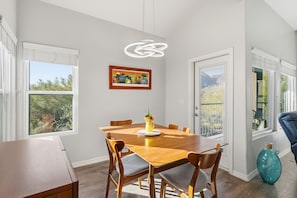 Ein Essbereich mit Holztisch, Stühlen, einer Vase mit Blumen und einem gerahmten Bild an der Wand.