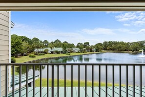 A view of a lake with a fountain, surrounded by trees and buildings with green roofs. - 🦩Book Me Baby! See You at the Bayou in Miramar Beach🦩 (Miramar Beach)