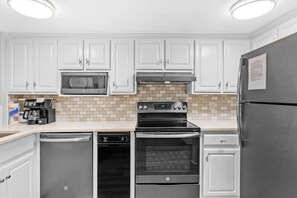 A kitchen with white cabinets, a microwave, a stove, a dishwasher, and a refrigerator. - 🦩Book Me Baby! See You at the Bayou in Miramar Beach🦩 (Miramar Beach)