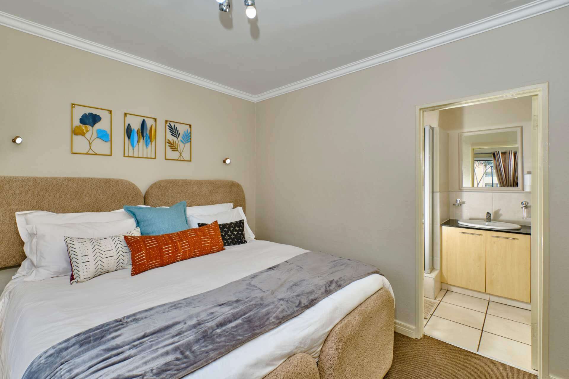 Een hotelkamer met een bed, een badkamer met een wastafel en een deur naar een andere kamer.