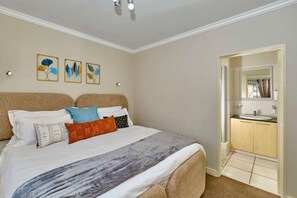 Habitación de hotel con cama, baño con lavamanos y puerta que da a otra habitación.