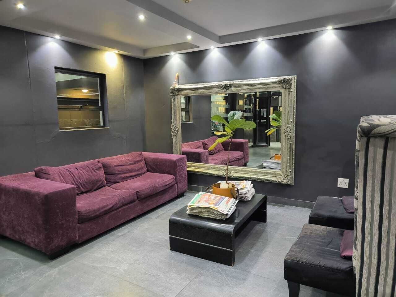A modern living room with a large mirror, a purple sofa, a coffee table, and a small side table.