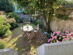 A garden with a table and chairs, a bench, and a tree. - Charming house in the city center, just a stone's throw from the ocean, with a small garden (Saint-Nazaire)