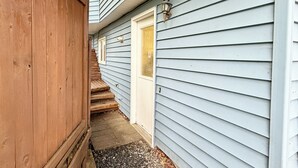 A narrow pathway leading to a door with a light fixture above it.