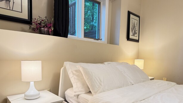 A bedroom with a bed, bedside tables, a window, and wall-mounted artwork.