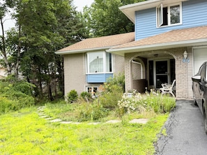 A two-story house with a brick exterior, a front porch, and a car parked in the driveway. - Beautiful 2-bedroom basement in quaint Bedford perfect for relaxing stays (Bedford)