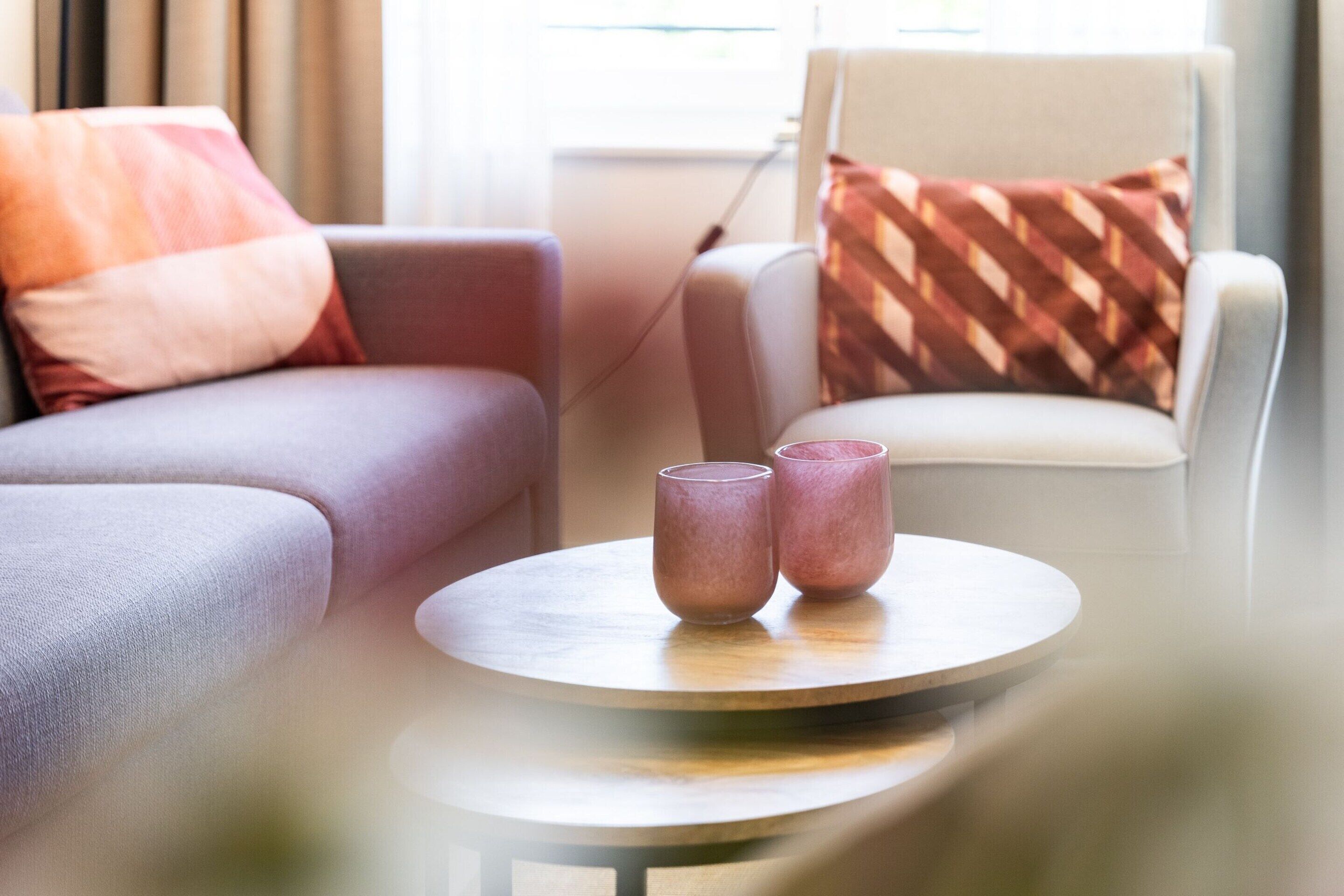 A modern living room with a round coffee table, two glass containers, a sofa, and a chair.