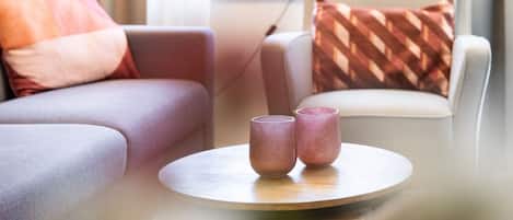 A modern living room with a round coffee table, two glass containers, a sofa, and a chair.