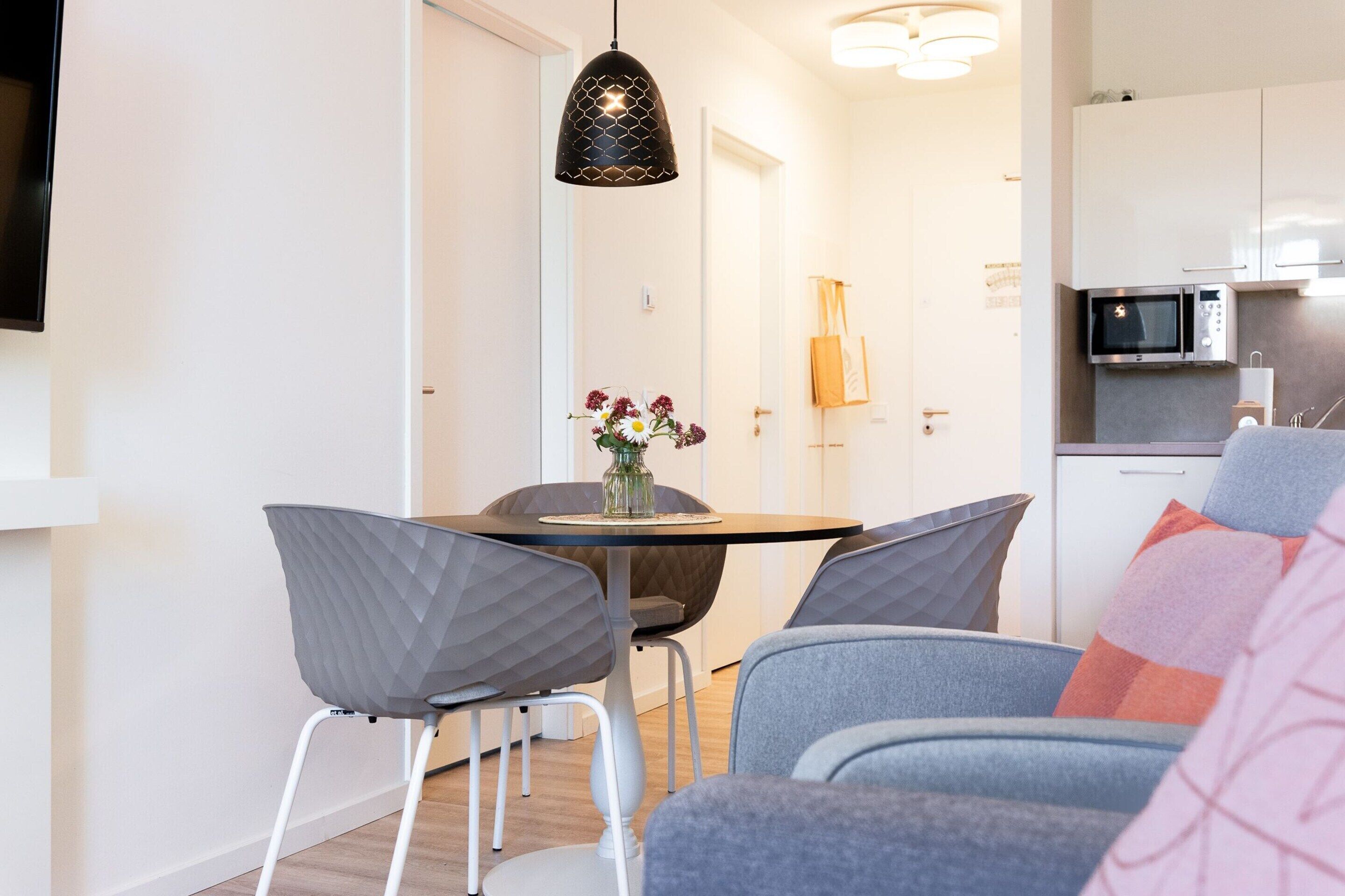 Cozinha moderna com micro-ondas, máquina de café e área de refeições com mesa e cadeiras.