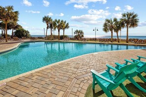 A swimming pool with lounge chairs and palm trees, surrounded by a brick patio. - A polished oceanfront escape where subtle JAWS-inspired details, thoughtful luxury, and dog-friendly comforts create an unforgettable beach getaway. (Myrtle Beach)