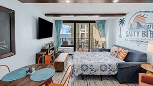 Una habitación compacta con cama, sofá, mesa de comedor y televisor.
