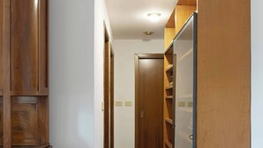 A hallway with wooden cabinets, a wardrobe, and a bed. - Parthenope | Bright 1BR nest in a residential area (Milan)