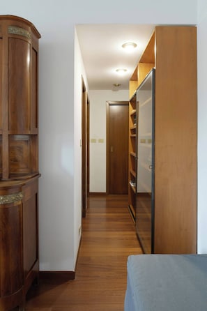 A hallway with wooden cabinets, a wardrobe, and a bed. - Parthenope | Bright 1BR nest in a residential area (Milan)