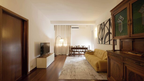 A living room with a sofa, TV, wooden cabinet, and artwork on the wall. - Parthenope | Bright 1BR nest in a residential area (Milan)