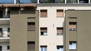 A multi-story building with balconies, a ground-level office, and a visible storefront. - Parthenope | Bright 1BR nest in a residential area (Milan)