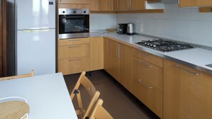 A kitchen with wooden cabinets, a white countertop, a stove, an oven, and a refrigerator. - Parthenope | Bright 1BR nest in a residential area (Milan)