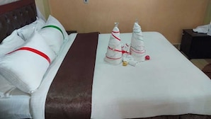 A hotel room with a bed, a nightstand, and two Christmas tree decorations.