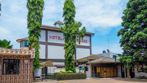 Un hotel con un llamativo letrero que dice 'HOTEL', fachada de piedra y un área de entrada pavimentada.