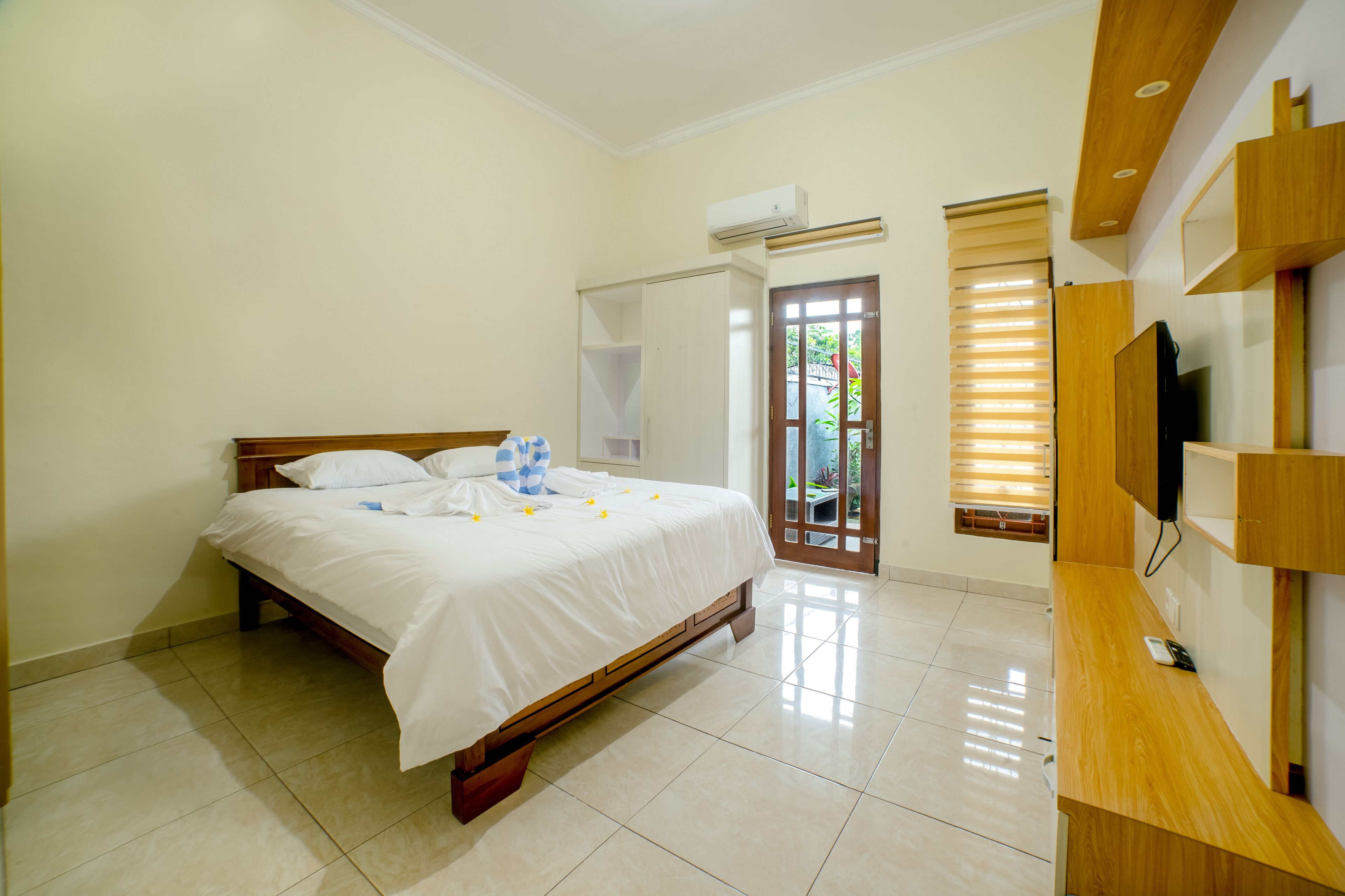 Una habitación de hotel con una cama, un televisor y una puerta que da a un balcón.