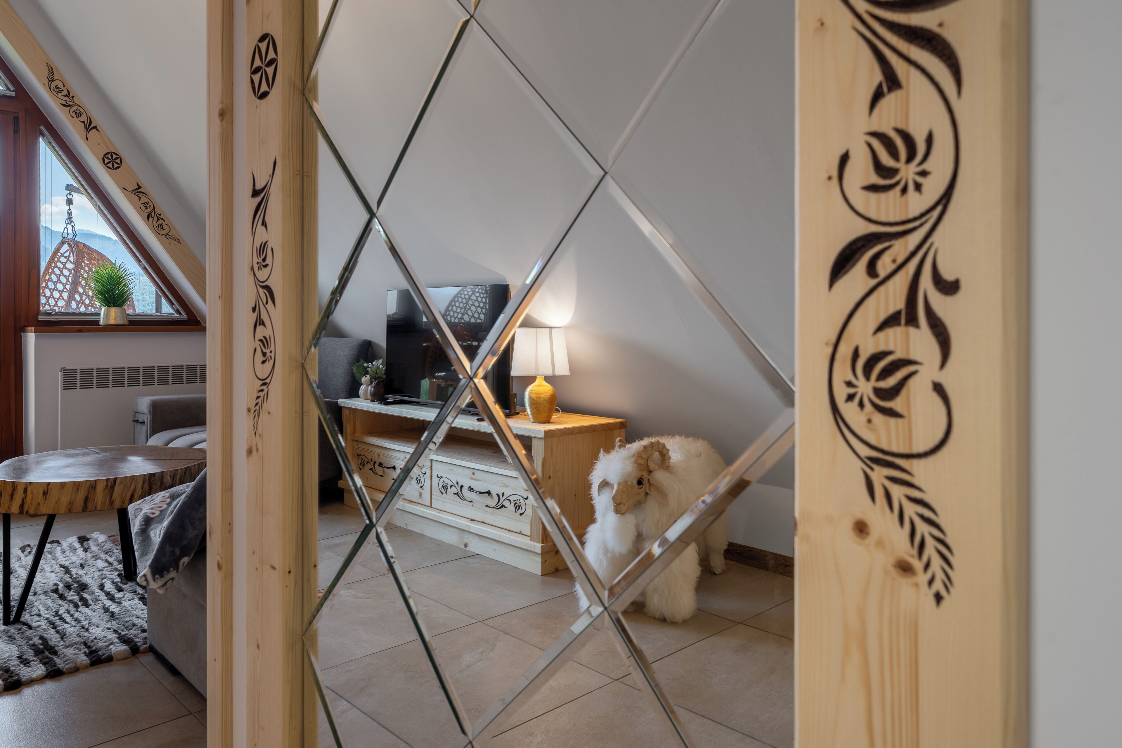 Een kamer met een houten scheiding, een bank, een lamp en een kleine witte hond.