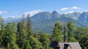 Eine Bergingerhütte mit geneigtem Dach, umgeben von dichtem Wald und einer Kulisse aus zerklüfteten Bergen.
