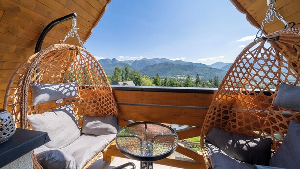 A wooden deck with two hanging chairs and a small table. - RentPlanet - Apartament Kierpcówka (Kościelisko)