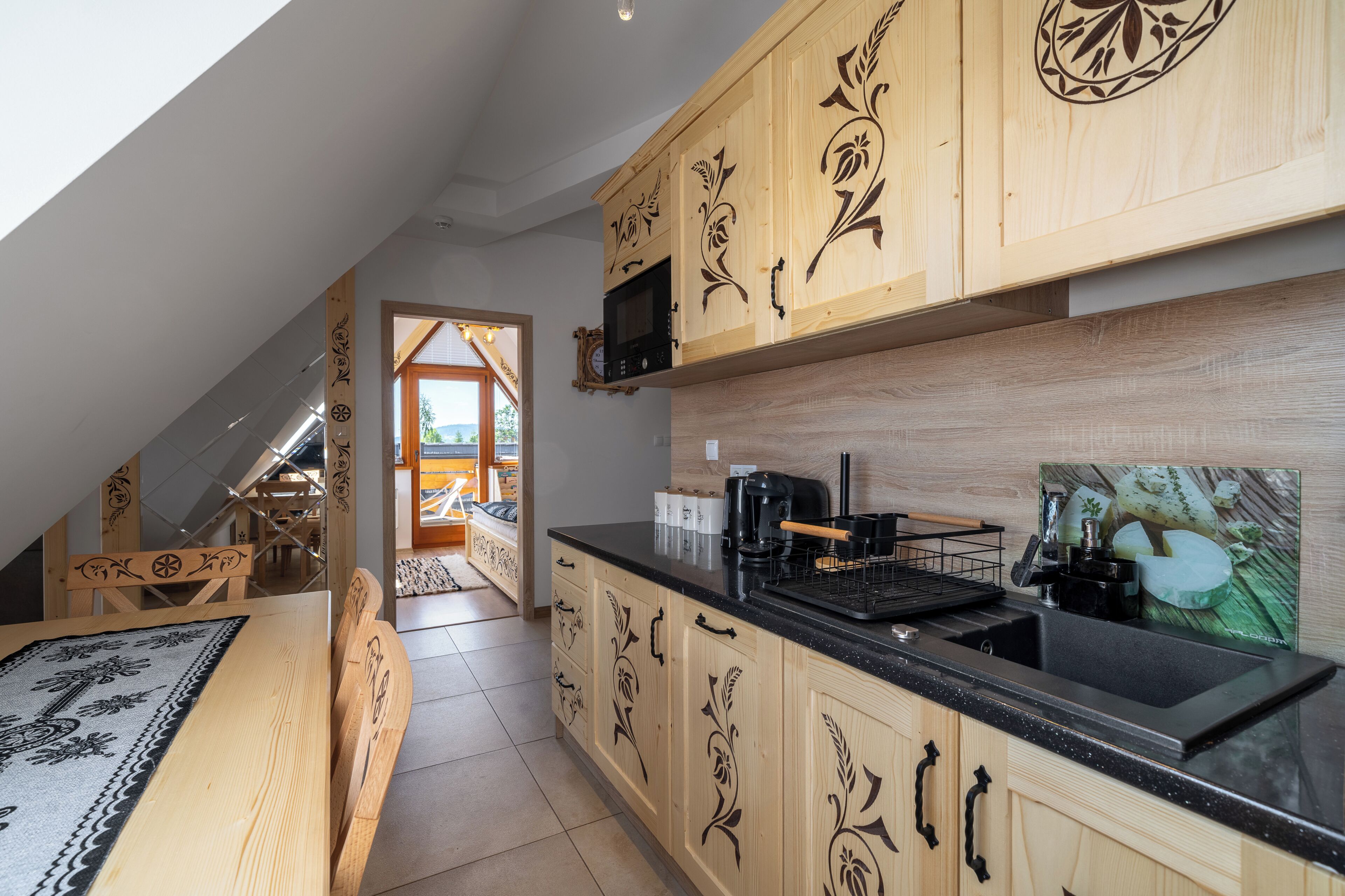 A kitchen with wooden cabinetry, a black countertop, and a microwave.