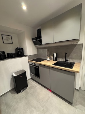A modern kitchen with a built-in oven, a coffee machine, and a sink.