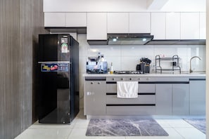 A modern kitchen with a black refrigerator, a gas stove, and grey cabinetry. - The Westlands Haven, 2BR,  2 King Beds, Walk to Sarit & GTC,  Gym + Balcony (Nairobi)