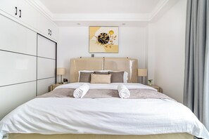 A hotel room with a bed, bedside tables, a headboard, and a wall-mounted artwork. - The Westlands Haven, 2BR,  2 King Beds, Walk to Sarit & GTC,  Gym + Balcony (Nairobi)