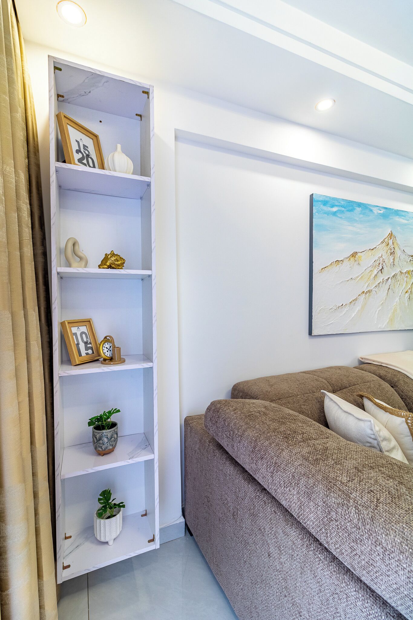 A bedroom with a bed, a white shelving unit with decorative items, and a painting on the wall.