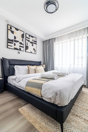 Ein modernes Schlafzimmer mit einem schwarzen Bett, weißer Bettwäsche und einem gemusterten Teppich.