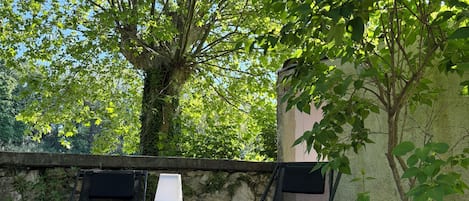 An outdoor patio with a round table, two chairs, and a lamp.