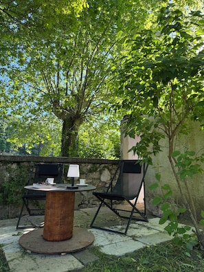 Eine Terrasse im Freien mit einem runden Tisch, zwei Stühlen und einer Lampe.