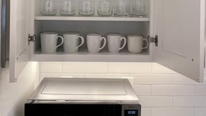 Un meuble de cuisine avec des étagères contenant divers articles en verre et des tasses.