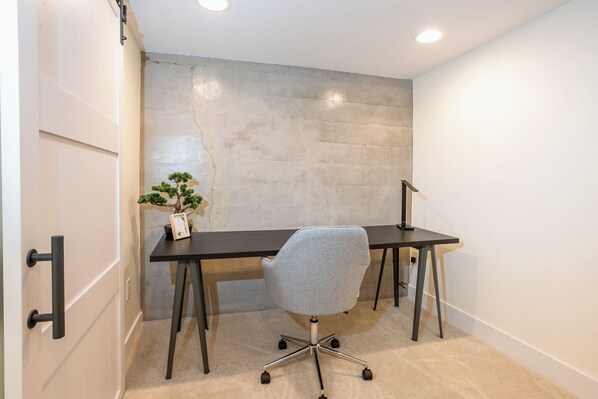 A modern office space with a desk, chair, and a potted plant.