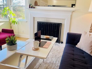 A living room with a fireplace, a sofa, a coffee table, and a potted plant.