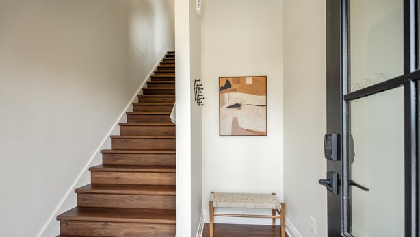 Eine Holztreppe führt zu einem Raum mit einer Bank und einem Gemälde an der Wand.