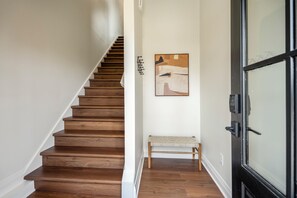 Eine Holztreppe führt zu einem Raum mit einer Bank und einem Gemälde an der Wand.