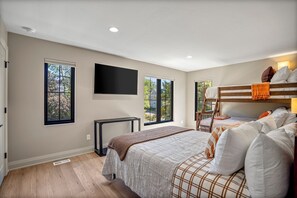 A bedroom with a large bed, a TV mounted on the wall, and two windows providing natural light. - CUSTOM FALCON PUTTING GREEN and Luxury combined to create your DREAM stay here in the heart of Bowling Green! (Bowling Green)