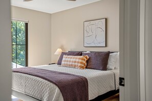 A bedroom with a bed, a window, a wall-mounted lamp, and a piece of abstract art. - CUSTOM FALCON PUTTING GREEN and Luxury combined to create your DREAM stay here in the heart of Bowling Green! (Bowling Green)