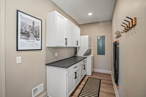 A narrow hallway with white cabinetry, a framed picture on the wall, and a coat rack. - CUSTOM FALCON PUTTING GREEN and Luxury combined to create your DREAM stay here in the heart of Bowling Green! (Bowling Green)