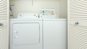 Un lavadero con dos lavadoras blancas y una secadora.