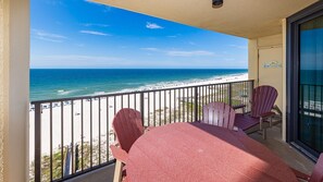 A balcony with a view of the beach, a table, and two chairs. - Phoenix Iv 4082 1 Bedroom Condo (Orange Beach)