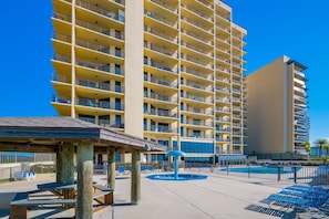 Un hotel de varios pisos con balcones, piscina y zona de estar techada.
